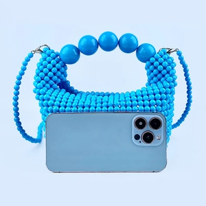 Close-up of a blue handmade beaded handbag with large bead handle and fine chain