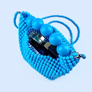 Detail of blue beaded mini crossbody bag showing interior storage for makeup and lipstick