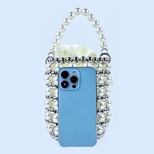 Detailed view of handmade pearl beaded bucket bag showing size compared to a smartphone
