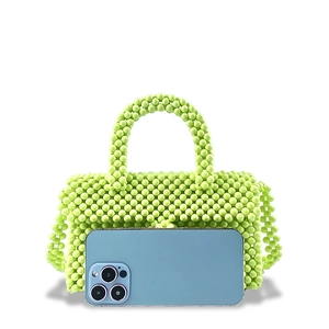 Neon green beaded handbag shown next to a smartphone to demonstrate size and scale