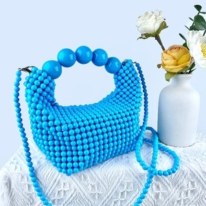 Detail of blue beaded handbag showing handmade weaving and large bead handle