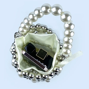 Detailed view of handmade pearl beaded bucket bag with white satin drawstring lining