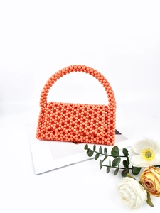 Detailed view of handmade orange beaded handbag with a unique hollowed-out woven design