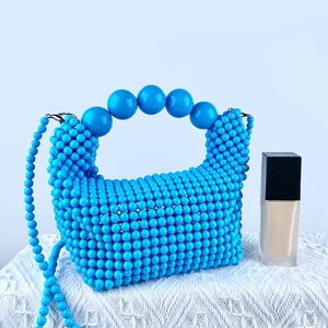 Detailed view of hand-woven bright blue beaded bag with large beads on handle