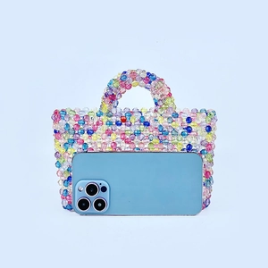 Handmade rainbow beaded handbag showing size comparison with a smartphone