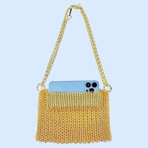 Detailed view of golden metal mesh crossbody bag holding a light blue smartphone