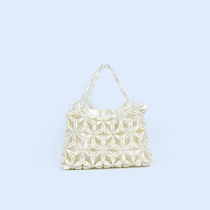 Close-up of handmade pearl handbag with floral weave patterns and silk lining