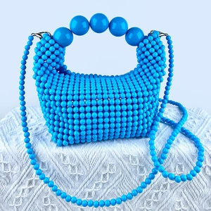 Detail of royal blue beaded handbag showing large ball handle and woven texture