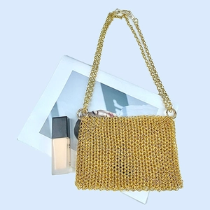 Macro shot of gold metal mesh handbag with fine chain link texture and crossbody strap