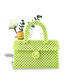 Detail of light green beaded handbag featuring floral bead buckle and woven handle