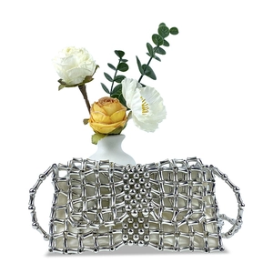 Detail of silver beaded bow evening clutch with elegant hollow metal mesh design