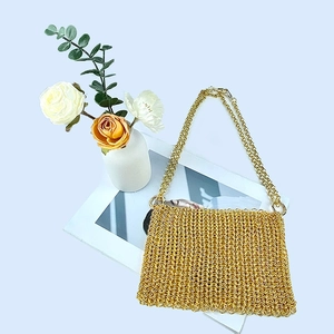 Detail of handcrafted gold metal chain link weaving on a luxury evening handbag