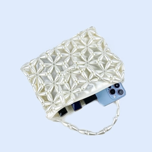 Detail view of pearl beaded bag interior showing phone and lipstick storage capacity
