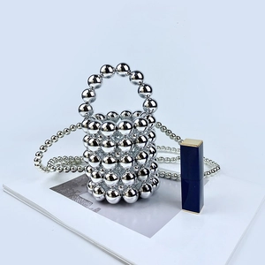 Mini silver beaded bucket bag with mirror finish pearl chain next to a lipstick