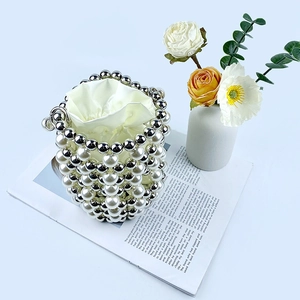 Top view of pearl and silver bead bucket bag with a satin drawstring pouch on a magazine