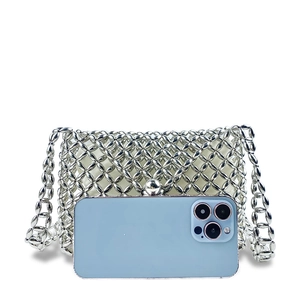 Detail of silver metallic woven crossbody bag with hollow floral pattern and shoulder strap