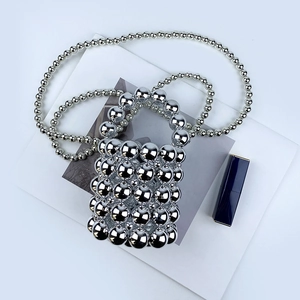 Close-up of a silver beaded mini bucket bag with metallic pearls and long cross-body strap