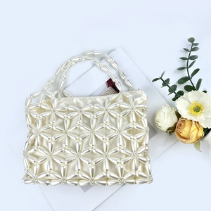 Detail of handmade pearl beaded handbag featuring intricate flower patterns and satin lining