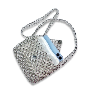 Detail of silver beaded crossbody bag showing capacity with a smartphone and white lining