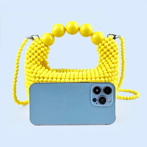 Macro shot of yellow handmade beaded handbag showing large bead handles and acrylic texture