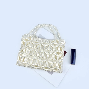 Detail showing pearl beaded floral pattern with elegant beige silk lining on the handbag