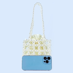 Detailed shot of handmade pearl handbag with satin liner and mobile phone for scale