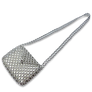 Detailed macro view of silver woven metal crossbody bag with mesh rings and snap buckle