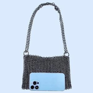 Detail of silver chainmail crossbody bag showing scale size next to a smartphone