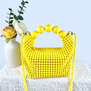 Detail of handmade bright yellow beaded handbag with large sphere handles and crossbody chain