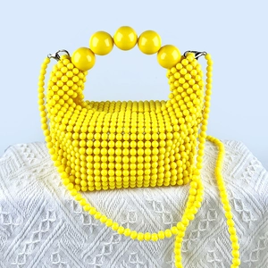 Detail view of handmade yellow beaded bag with large pearl handle and woven texture