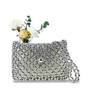 Detail of silver beaded crossbody bag featuring woven mesh texture and metal ball clasp