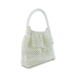 Close-up of elegant handmade woven cream pearl handbag with large decorative pearl clasp