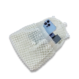 Macro detail of handmade pearl woven handbag showing capacity with phone and lipstick inside