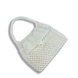 Detailed view of handmade white pearl beaded handbag with woven texture and top handle