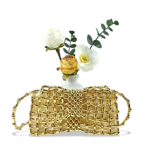 Detail of golden metal woven handbag with bamboo-style beads and bow silhouette