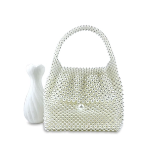 Close-up of handmade white pearl woven handbag with elegant trapezoid design and large pearl clasp