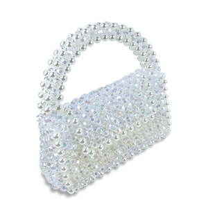 Gros plan de perles blanches et de perles de cristal acrylique sur un sac tissé main