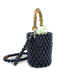 Detail der handgewebten schwarzen Perlen-Eimertasche mit Bambusgriff und Satinfutter
