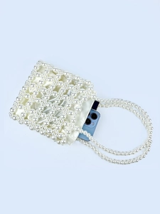 Handmade pearl beaded handbag with satin lining and top handles on a light blue background