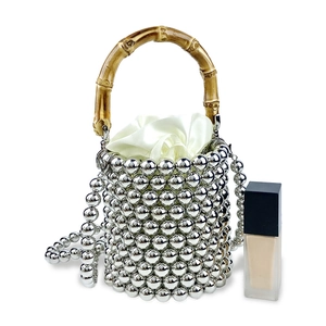 Detail der silbernen Perlenbeuteltasche mit Bambusgriff und weißem Satin-Kordelzugbeutel