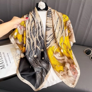 Carré en satin avec imprimé koi et fleurs jaunes présenté sur un canapé en cuir