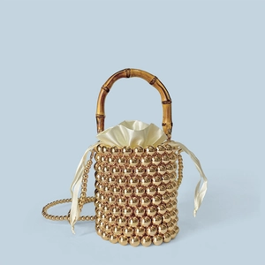 Details einer Perlen-Beuteltasche mit natürlichem Bambusgriff und goldenen Perlen