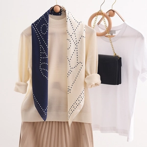 Elegant navy and beige polka dot silk scarf draped over a classic beige autumn outfit