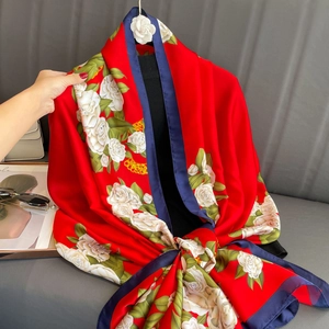Detail of red floral silk scarf with white camellia prints and navy blue hemmed edges