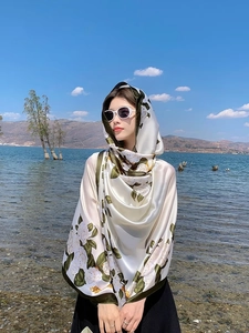 Detailed texture of white camellia floral print silk scarf with olive green borders