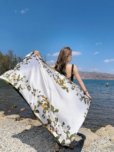 Floral silk shawl with green rose print on cream background in seaside setting