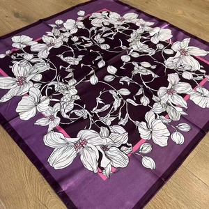 Close-up of purple floral silk scarf on wood texture showing detailed fabric and pattern