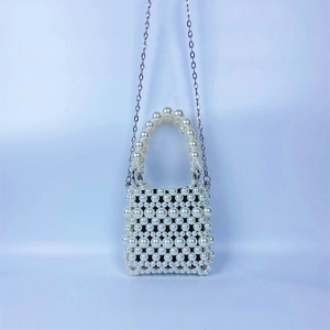 Détail d'un sac à main en perles tressées avec poignée ronde et fine chaîne en argent