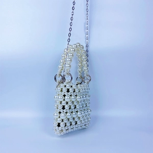 Détail d'un sac à main en perles tissées à la main avec chaîne métallique et perles blanches