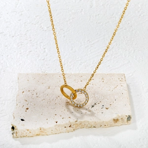 Elegant 18K gold-plated double ring necklace with sparkling crystals on a stone display